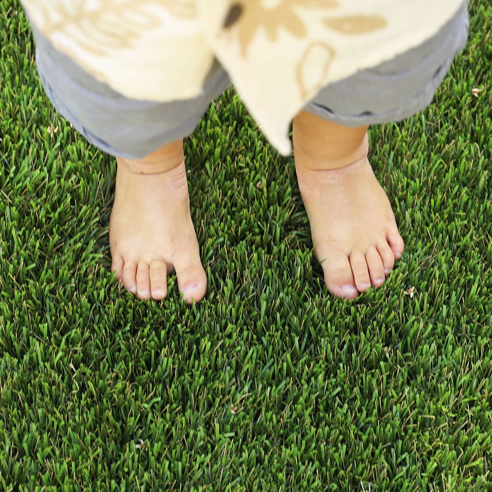 Child's bare feet standing on artificial turf